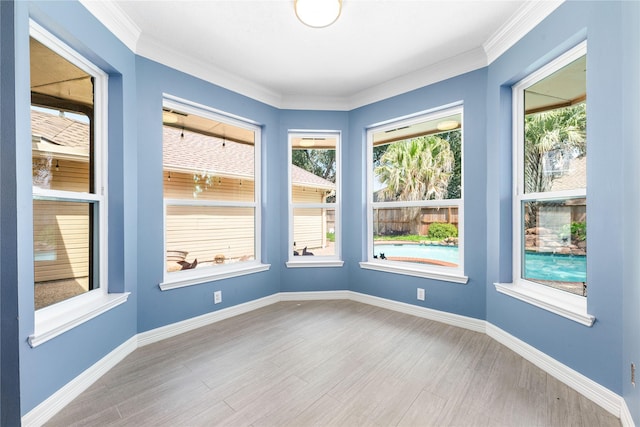 unfurnished room featuring wood finished floors, baseboards, and ornamental molding