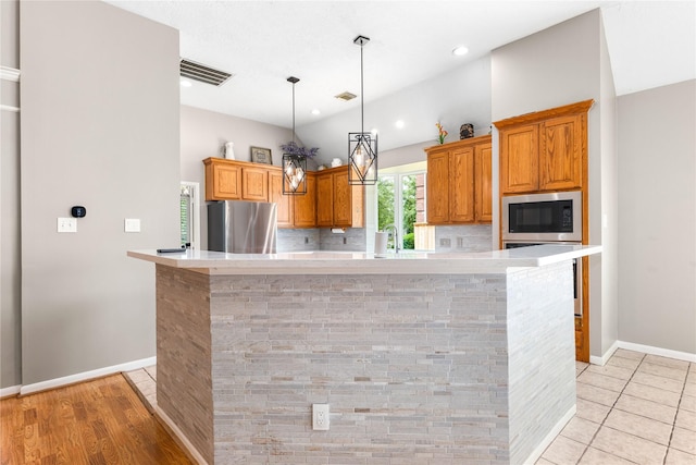 kitchen featuring baseboards, brown cabinets, light countertops, and stainless steel appliances