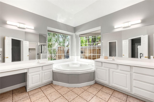 bathroom with tile patterned flooring, a sink, two vanities, and a bath