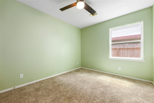 carpeted spare room featuring baseboards and ceiling fan