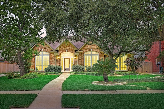 view of front of home featuring fence, a front lawn, and brick siding