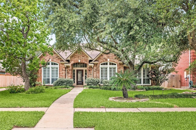 view of front of property with a front lawn, brick siding, and fence