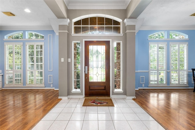 foyer entrance with ornamental molding, baseboards, and wood finished floors