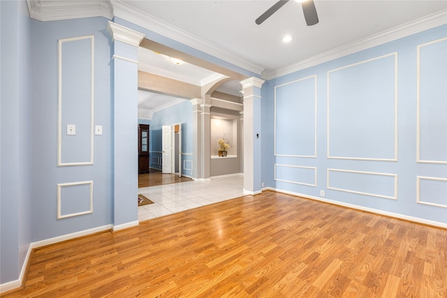 unfurnished room featuring wood finished floors, baseboards, a ceiling fan, and decorative columns