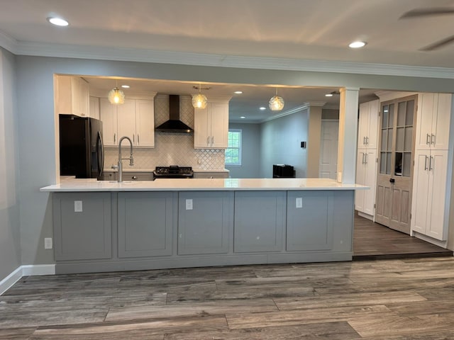 kitchen featuring wall chimney exhaust hood, dark wood-style floors, a sink, black appliances, and ornamental molding