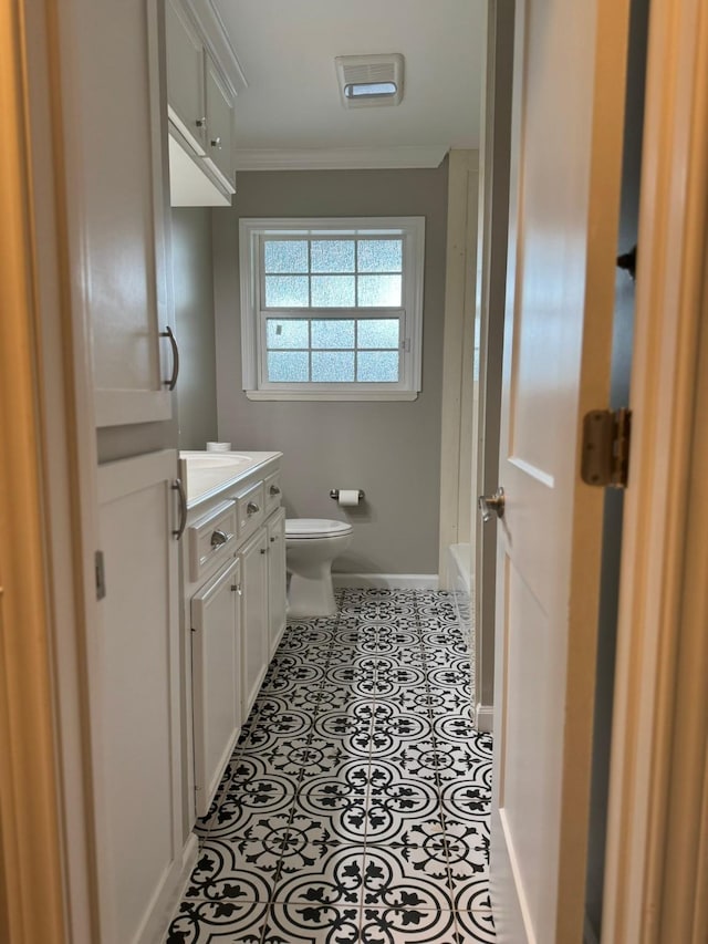 bathroom with a washtub, toilet, vanity, ornamental molding, and baseboards