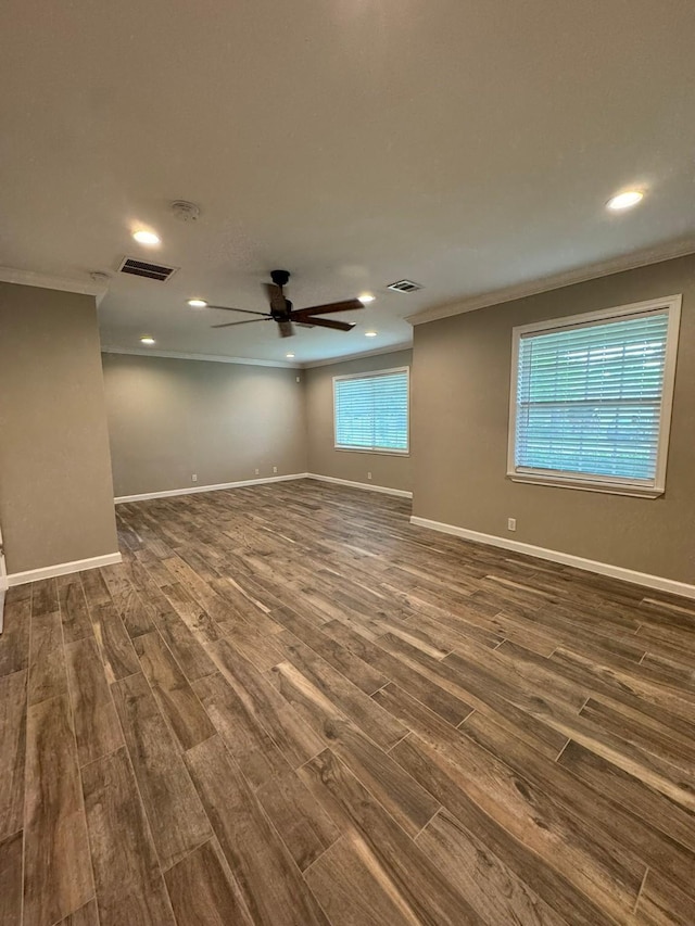 unfurnished room featuring visible vents, baseboards, a ceiling fan, crown molding, and dark wood-type flooring