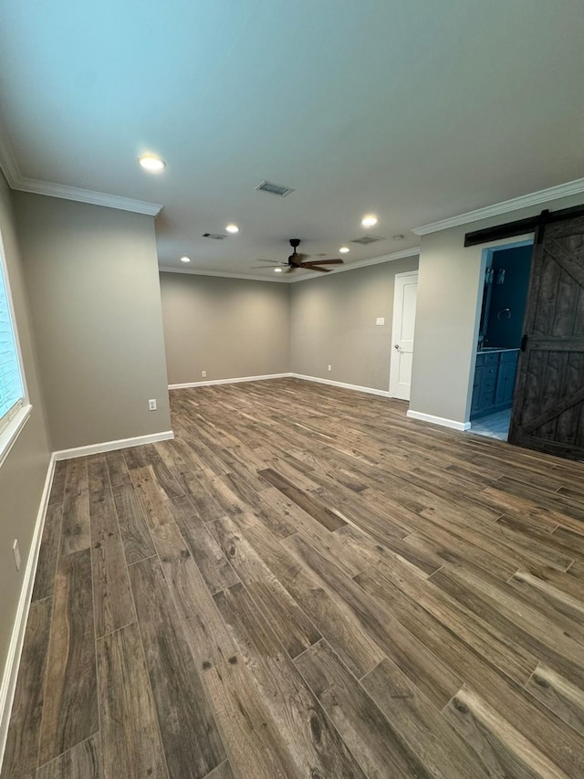 empty room featuring a barn door, recessed lighting, a ceiling fan, crown molding, and dark wood-style flooring
