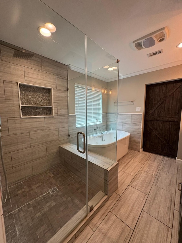 bathroom with a freestanding tub, tile walls, visible vents, and a shower stall