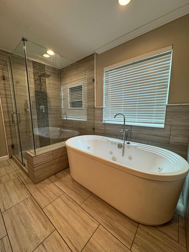 bathroom with tile walls, a freestanding tub, a shower stall, and crown molding
