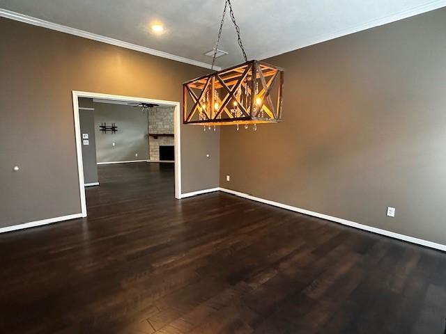 2407 Florence Dr, League City, TX 77573 - unfurnished dining area featuring baseboards, ornamental molding, a ceiling fan, a fireplace, and dark wood-type flooring