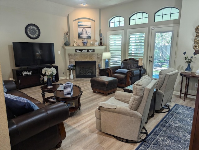 living area with baseboards, light wood finished floors, lofted ceiling, and a fireplace