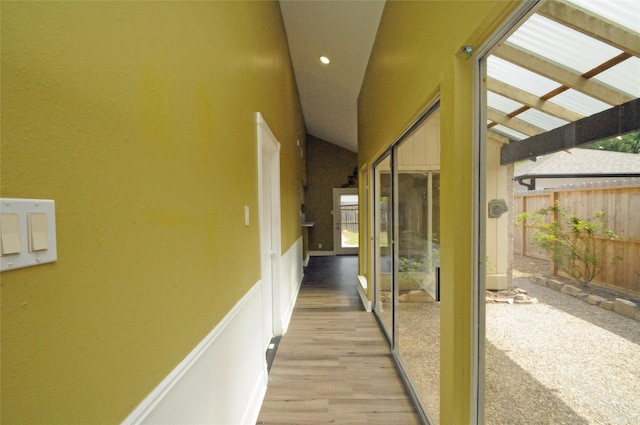 hallway with wood finished floors, recessed lighting, vaulted ceiling, and wainscoting