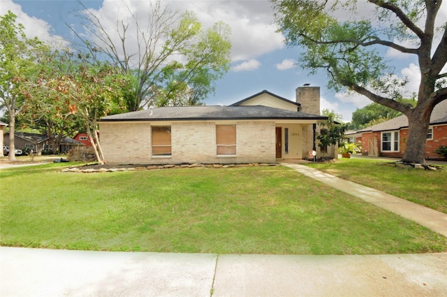 ranch-style home featuring a chimney, brick siding, and a front lawn