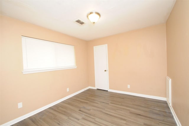 spare room with visible vents, wood finished floors, and baseboards