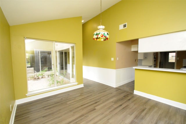 interior space featuring a wainscoted wall, wood finished floors, high vaulted ceiling, and visible vents