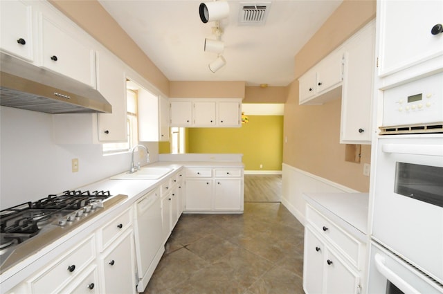 kitchen with white cabinetry, a sink, visible vents, under cabinet range hood, and white appliances