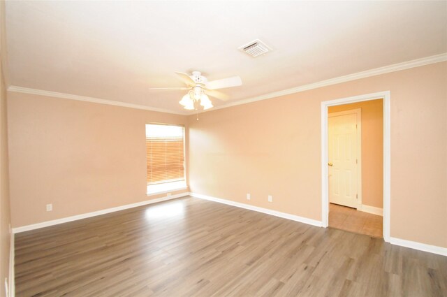 empty room with crown molding, visible vents, ceiling fan, and wood finished floors