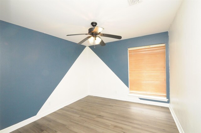 unfurnished room featuring baseboards, visible vents, wood finished floors, and ceiling fan