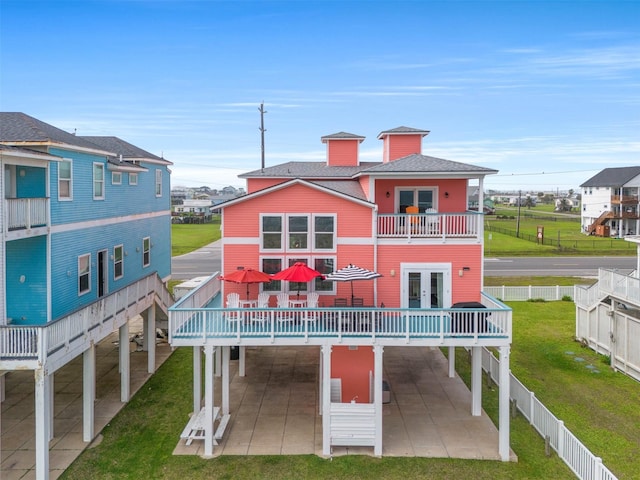 rear view of property with a carport, a balcony, a patio area, a fenced backyard, and a yard