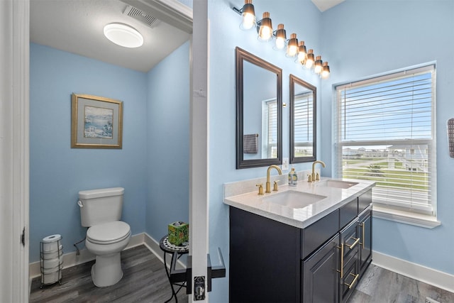 full bath with a sink, visible vents, toilet, and wood finished floors