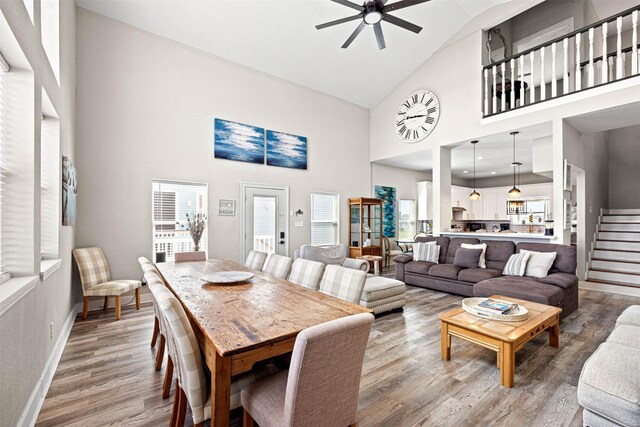 dining room featuring high vaulted ceiling, baseboards, wood finished floors, and ceiling fan