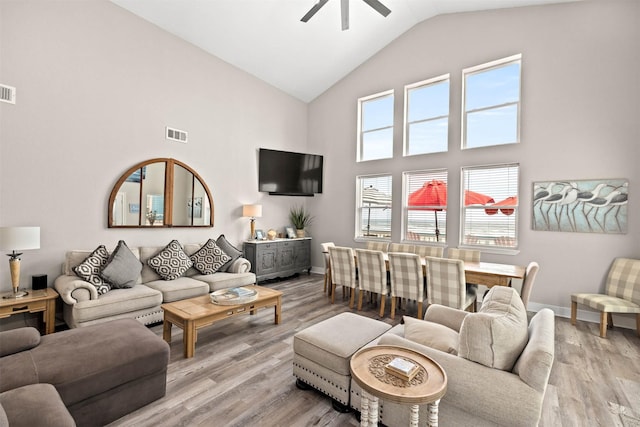 living room with high vaulted ceiling, light wood finished floors, visible vents, and ceiling fan