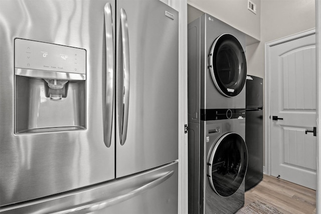 washroom with light wood finished floors, stacked washer / dryer, laundry area, and visible vents