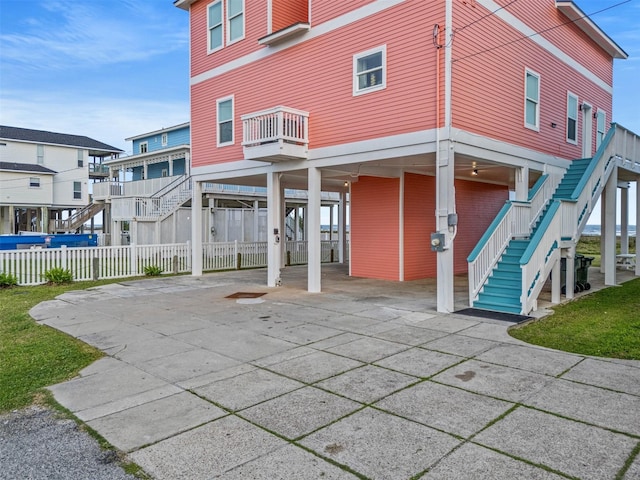 back of property featuring a carport, fence, stairs, and concrete driveway