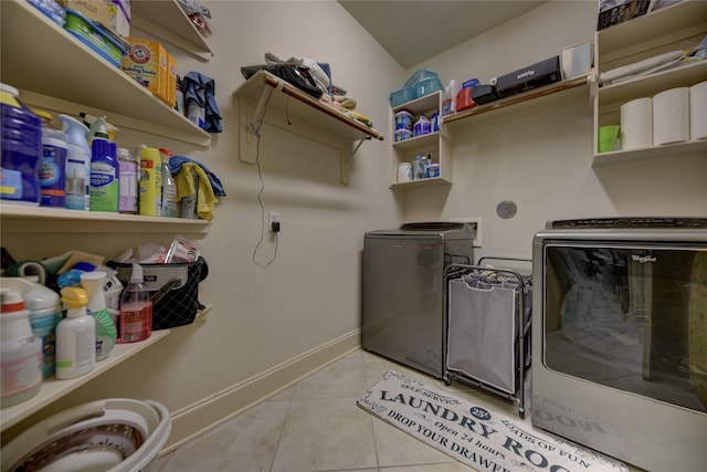 clothes washing area featuring laundry area, light tile patterned flooring, baseboards, and washer and clothes dryer