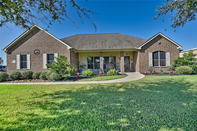 single story home featuring roof with shingles, a front yard, and brick siding