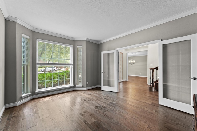 2023 Forest Garden Dr, Kingwood, TX 77345 - spare room with ornamental molding, a chandelier, a textured ceiling, dark wood-style floors, and baseboards