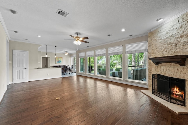 2023 Forest Garden Dr, Kingwood, TX 77345 - unfurnished living room featuring crown molding, a ceiling fan, a textured ceiling, dark wood-type flooring, and a stone fireplace