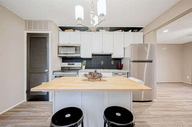 kitchen with visible vents, a textured ceiling, stainless steel appliances, butcher block countertops, and light wood-style flooring
