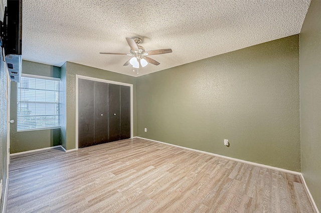 unfurnished bedroom featuring baseboards, a closet, a textured ceiling, a ceiling fan, and light wood-style floors