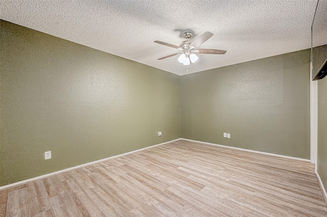 unfurnished room featuring wood finished floors, a textured wall, baseboards, and a ceiling fan