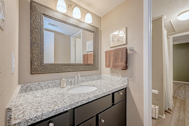 bathroom featuring a textured ceiling, vanity, and visible vents