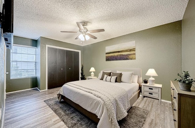 bedroom featuring light wood-style flooring, a closet, and a textured wall