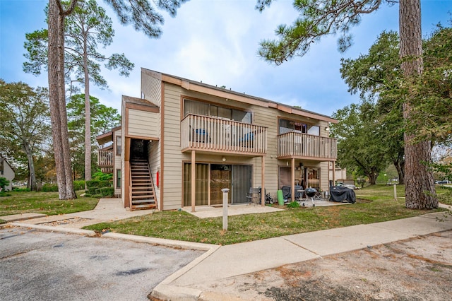 exterior space with uncovered parking, a yard, a patio area, and stairs