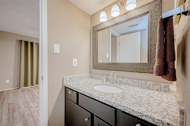 bathroom featuring visible vents, vanity, wood finished floors, and a textured ceiling
