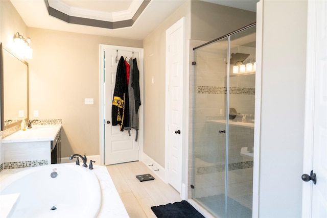 bathroom featuring crown molding, a tray ceiling, a stall shower, a garden tub, and vanity