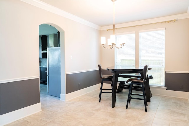 dining area with a chandelier, crown molding, baseboards, and arched walkways