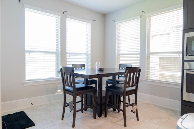 dining space featuring baseboards, light tile patterned floors, and a wealth of natural light