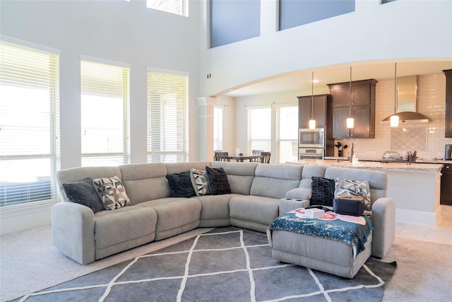 living room with visible vents, decorative columns, arched walkways, and light colored carpet