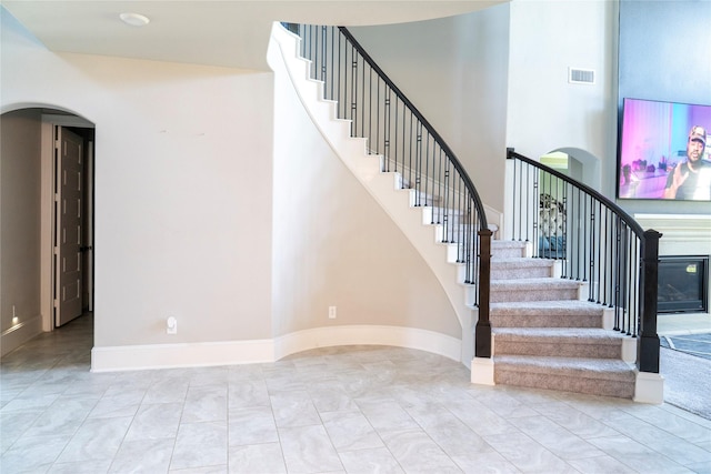 stairway with a towering ceiling, arched walkways, visible vents, and baseboards