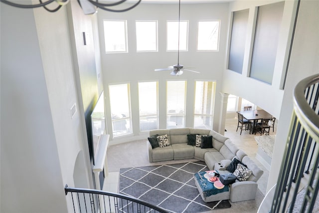 living room with a ceiling fan, a high ceiling, and decorative columns
