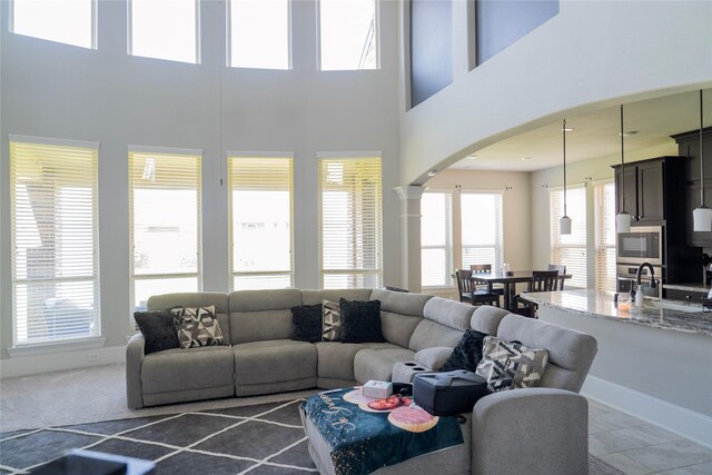 living area featuring a towering ceiling, baseboards, and arched walkways