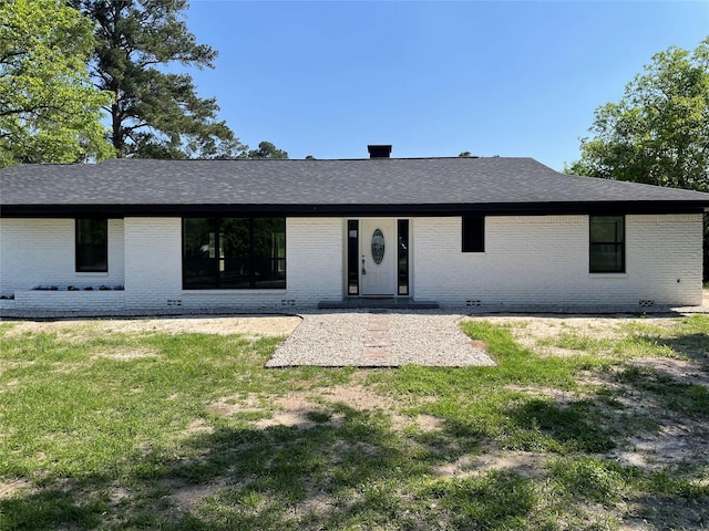 ranch-style home featuring brick siding, a front yard, and roof with shingles