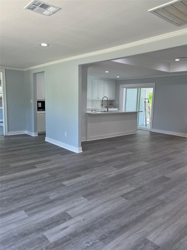 unfurnished living room featuring dark wood-type flooring, crown molding, baseboards, and visible vents