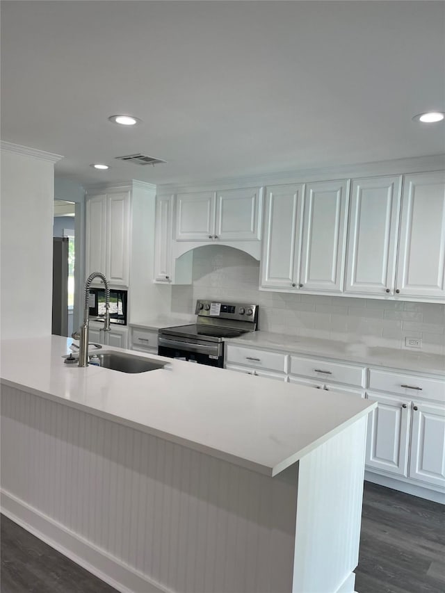 kitchen with white cabinets, recessed lighting, a sink, electric stove, and backsplash